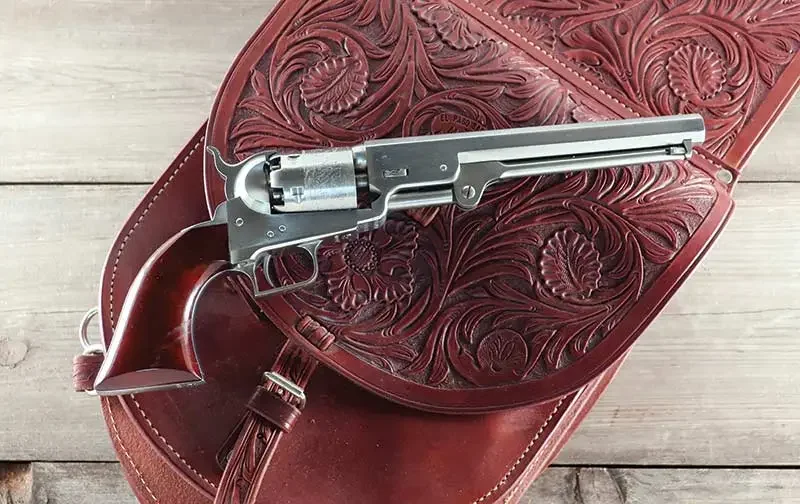 Револьвер «Морской» второго поколения из нержавеющей стали 1851 года лежит на прекрасных резных седельных сумках из седельной мастерской в Эль-Пасо