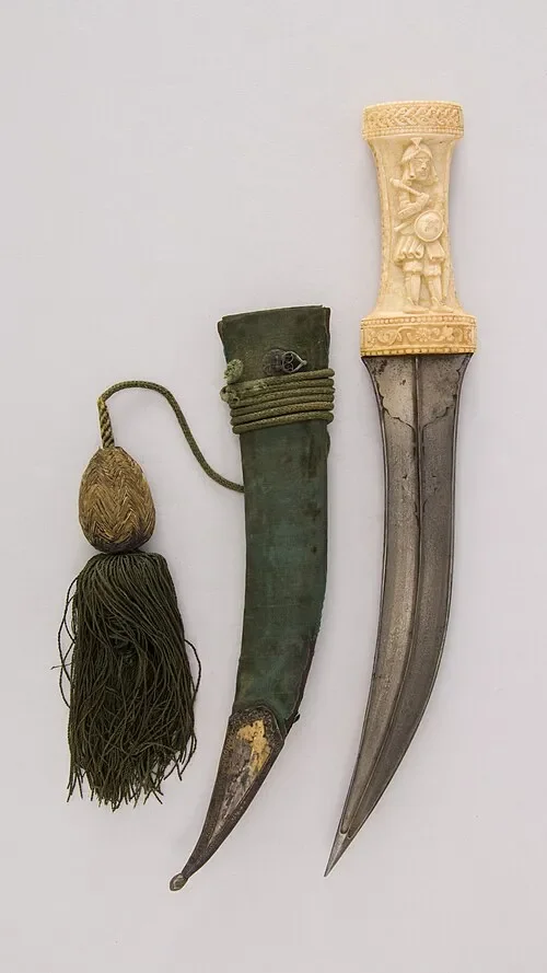Персидский кинжал с ножнами и шнуром. На рукояти изображён воин. Метрополитен-музей, Нью-Йорк.